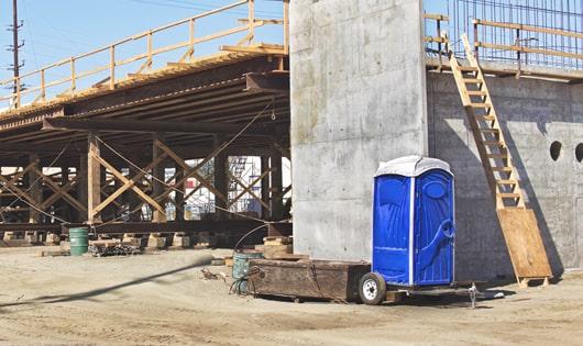 a row of modern porta potties at a busy construction site, designed for easy use and maintenance